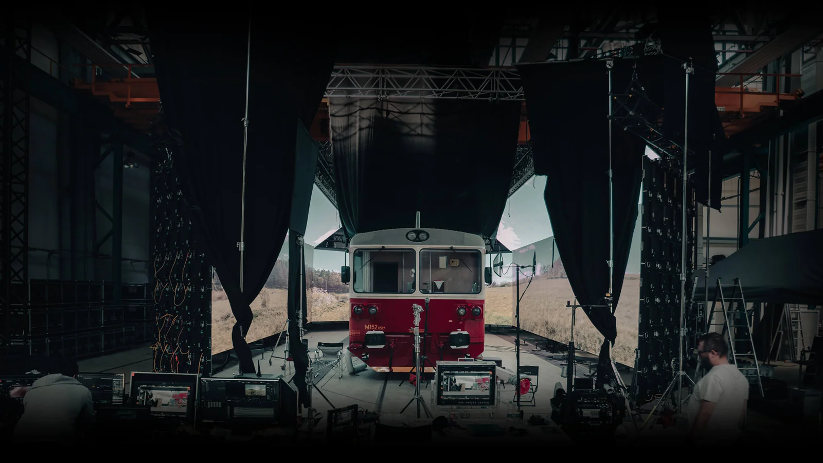 A red train on the VFXR virtual production stage, surrounded by LED walls showing a landscape